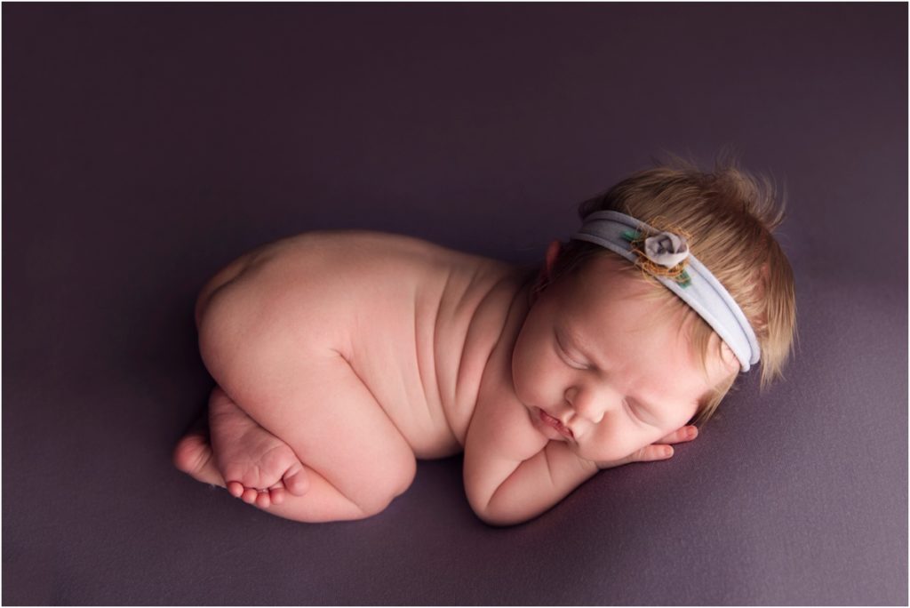 newborn baby girl on purple backdrop