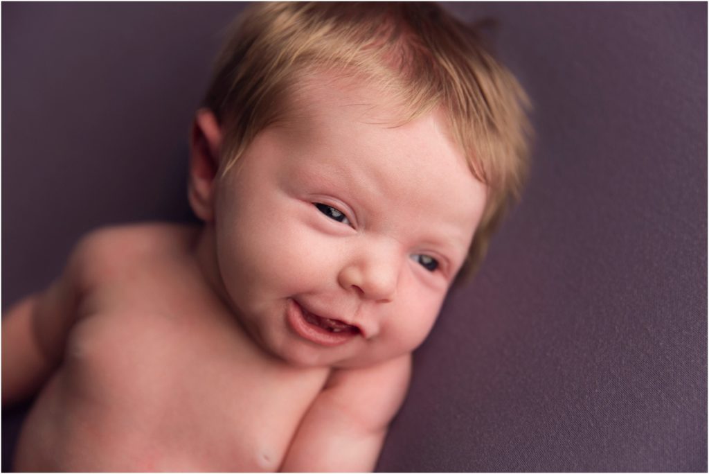Newborn Baby Smiles on Purple Blanket
